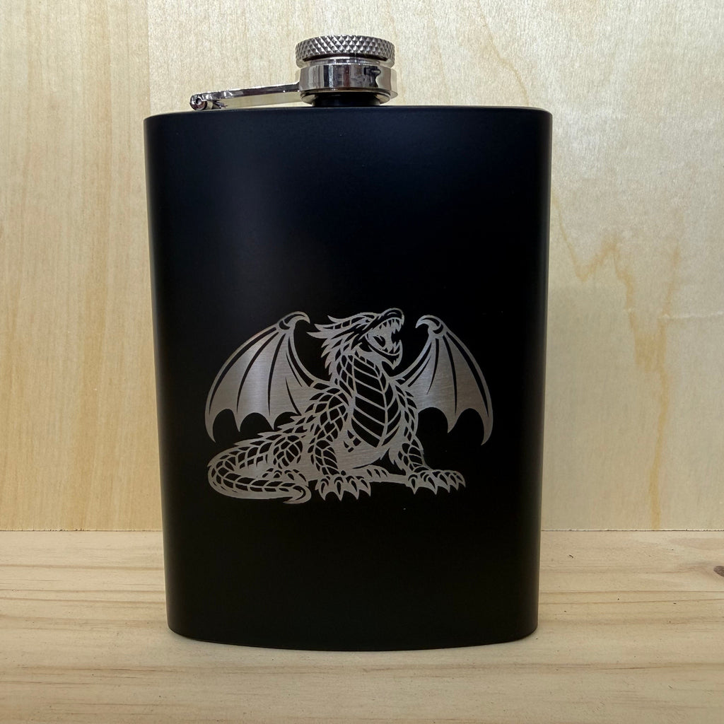 Black flask with a silver dragon design on a wooden surface