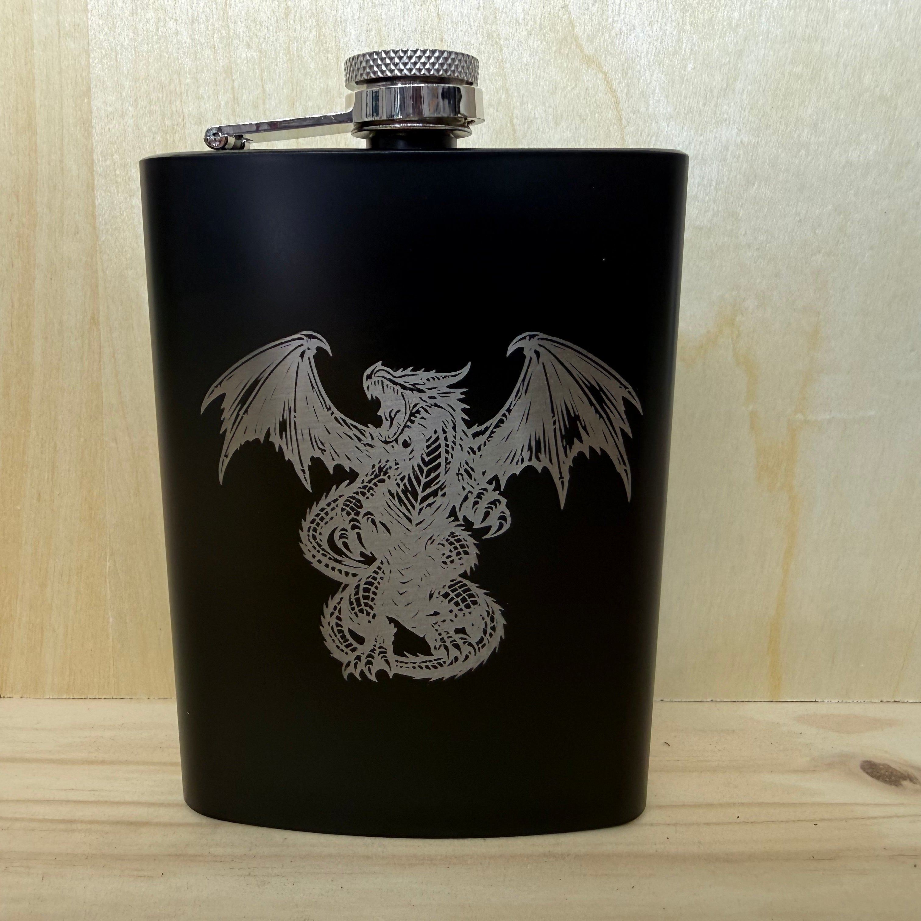 Black flask with dragon design on a wooden surface
