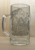 Glass mug with engraved fairy design on a wooden surface
