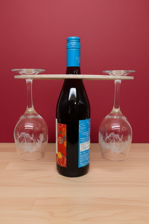 Wine bottle with blue label and two wine glasses on a wooden surface
