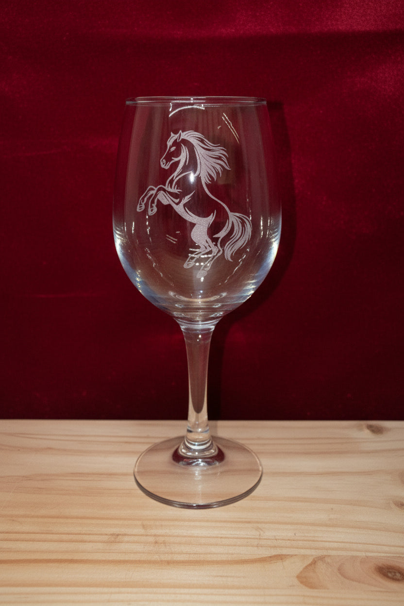 Clear glass wine glass with horse engraving on a wooden surface